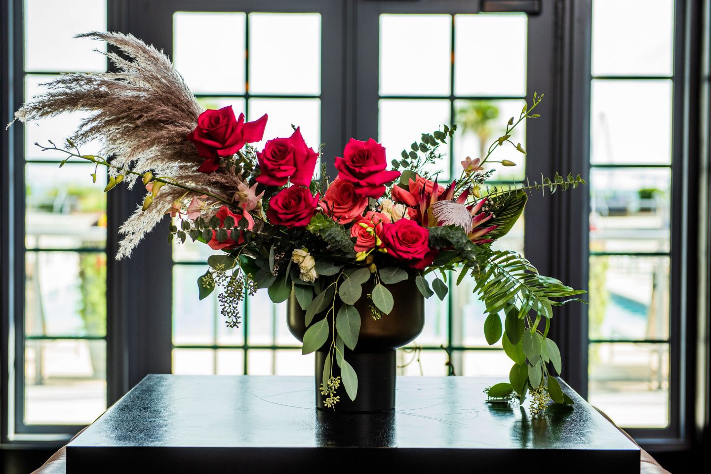 Boone's Blooms signature design for hotel lobby. Red roses and tropical flowers artfully designed to delight guests. Charleston, SC hotel florist. Florist for hospitality, restaurants and retail in Charleston. Mt Pleasant luxury florist. Elevated flowers