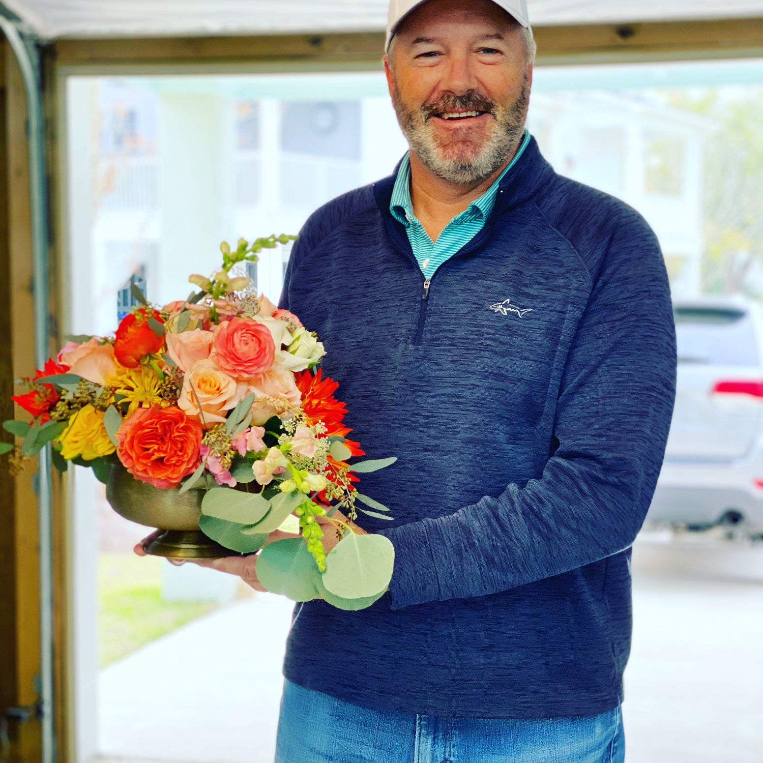 Thanksgiving centerpiece delivery in Mt Pleasant.  Smiling delivery man with flowers from Boone's Blooms. Pretty oranges and yellow fall flowers.